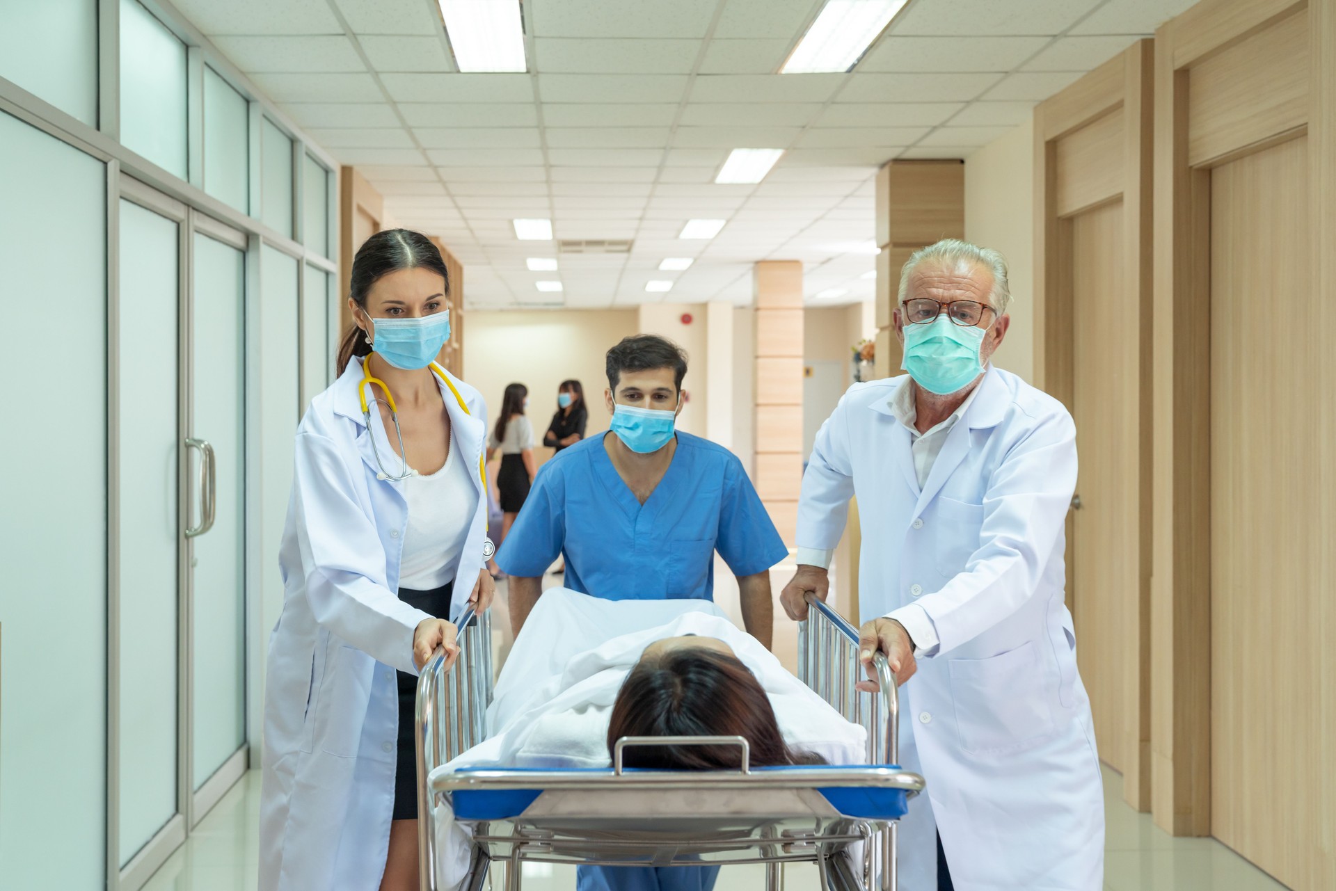 Caucasian doctor and Asian male nurse moving injured patient from an accident on a gurney to the emergency operating room